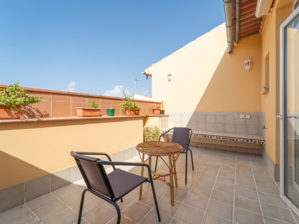 Terraza privada soleada de un piso en alquiler en Ses Salines, con mesa, sillas y macetas.