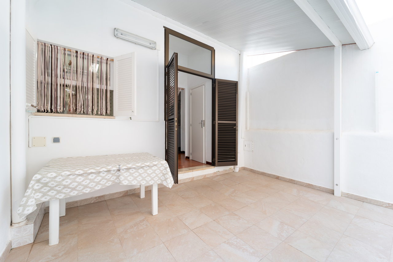Terraza cubierta con mesa y acceso al interior de la vivienda.