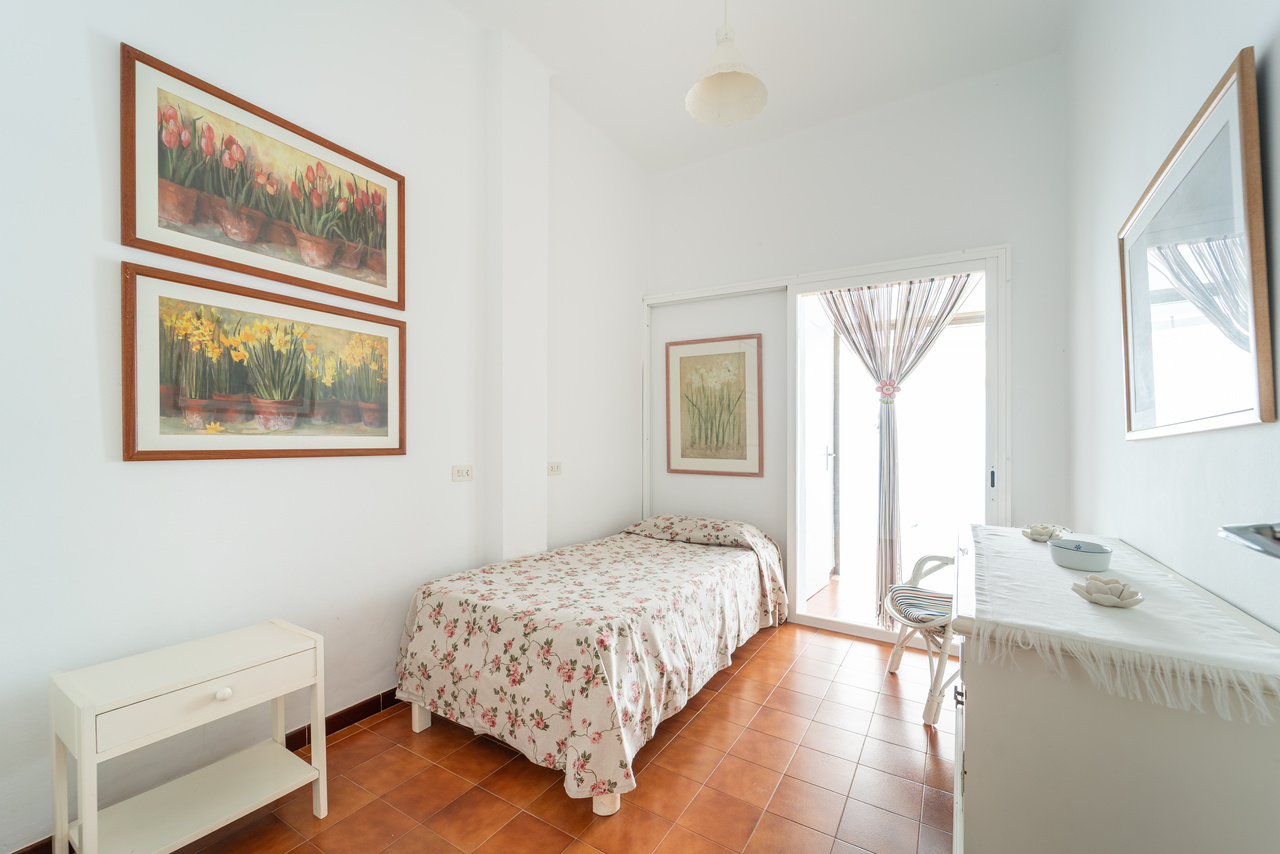 Dormitorio con cama, mesita blanca, cómoda y ventana.