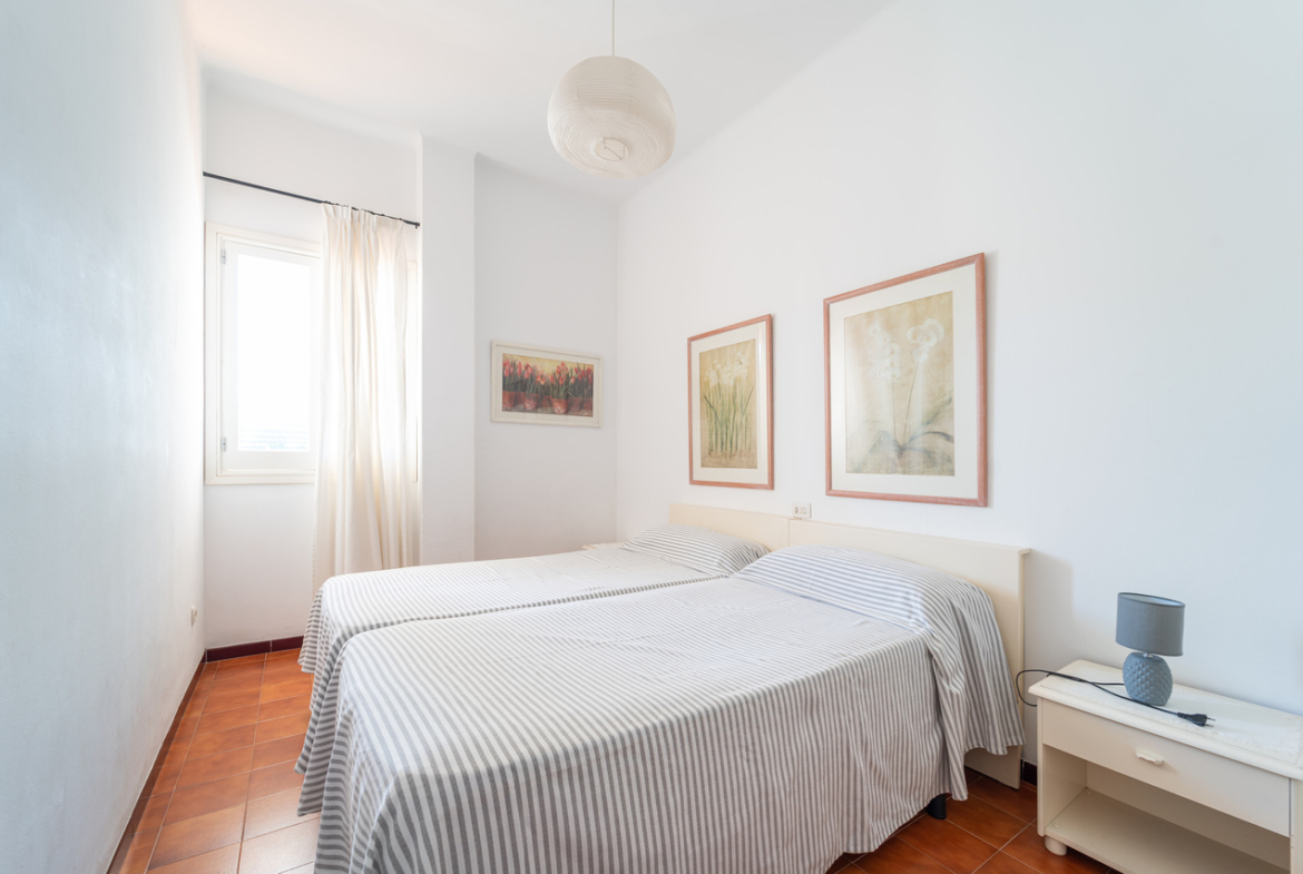 Dormitorio con dos camas individuales, mesita y lámpara.