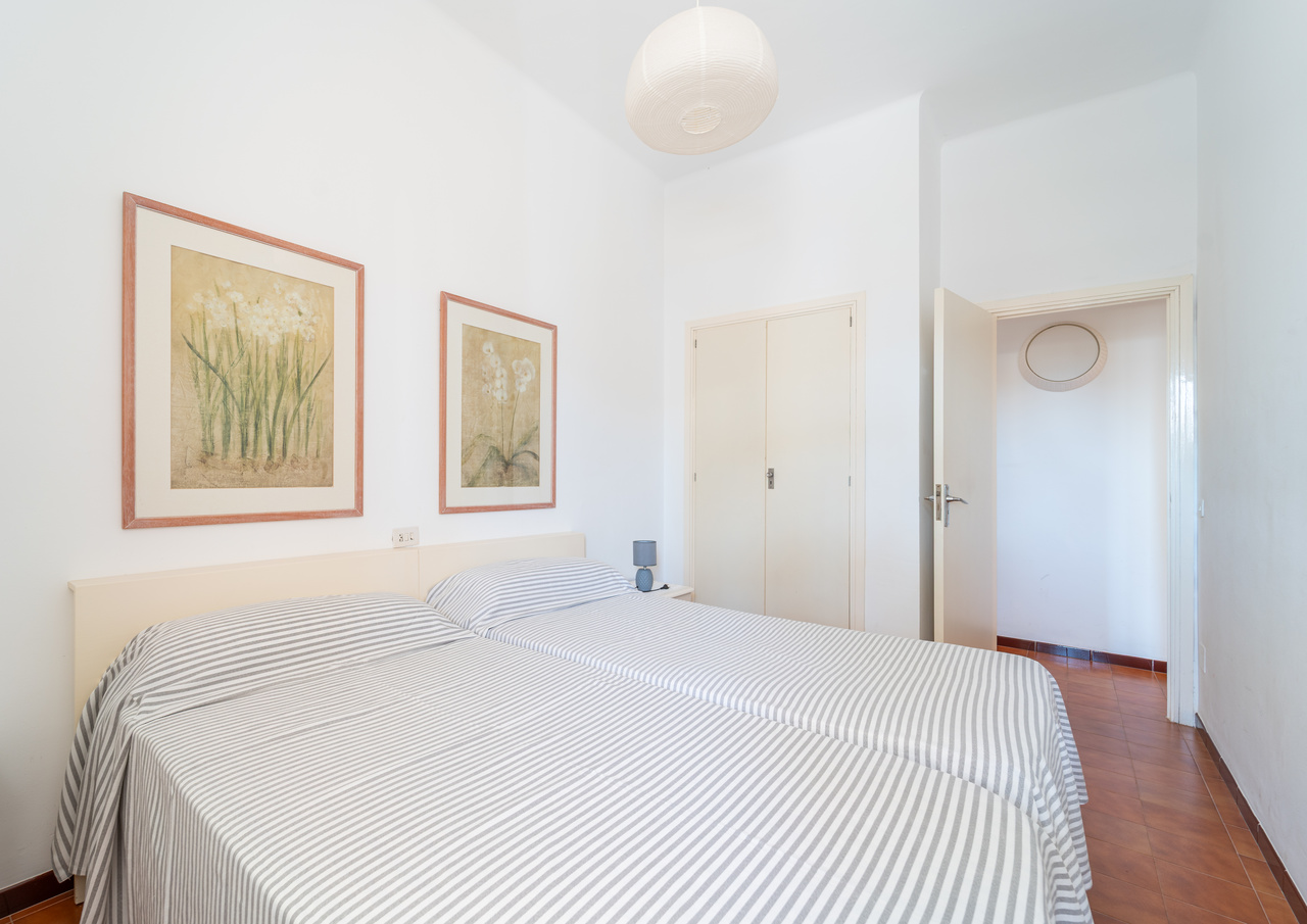 Dormitorio con cama doble, cuadros enmarcados y armario.