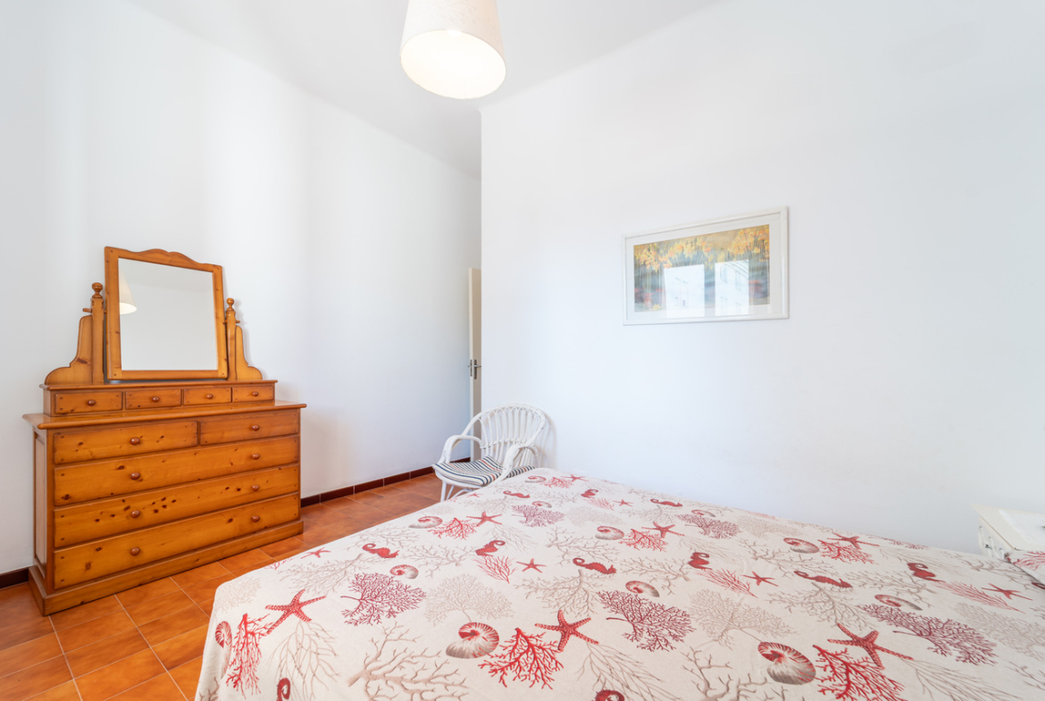 Dormitorio con cómoda de madera con espejo, cama doble y cuadro enmarcado.